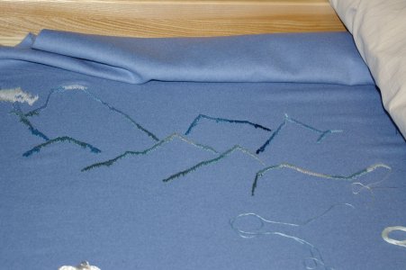 Blauer Radmantel, im Stickrahmen eingespannt, Hochgebirgsszene, 2-fädiger Sticktwist in blau und grün.